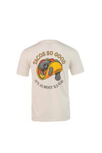 A cream-colored short-sleeve t-shirt shown from the back, featuring a large graphic of a gray dog inside a taco with the text 'TACOS SO GOOD' and 'IT'S ALMOST ILL GAL'.