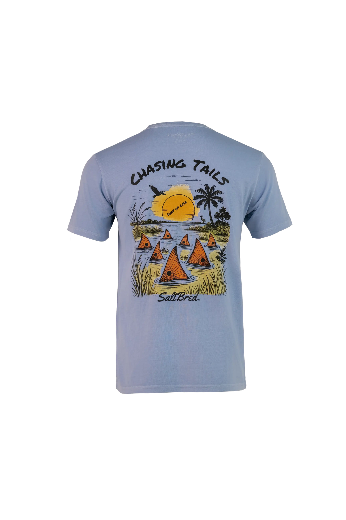 A light blue short-sleeve t-shirt shown from the back, featuring a colorful graphic print of sailboats on water with palm trees and a yellow sun, with the text 'CHASING TAILS' and 'Salt Bridge' printed on the design.