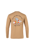 A tan long-sleeve t-shirt with a graphic on the back featuring a cartoon sea turtle carrying a surfboard, with the text 'Surf for the Sea Cows' and 'way of life'.
