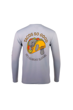 A light gray long-sleeve performance shirt shown from the back, featuring a large graphic of a gray alligator inside a taco with the text 'TACOS SO GOOD' and 'IT'S ALMOST ILLEGAL'.