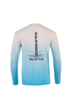A long-sleeve performance shirt shown from the back, featuring a white-to-light-blue gradient with a black vertical graphic reading 'SALTBRED WAY OF LIFE' and wave details.