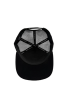 Black trucker cap shown from the back, featuring a solid black fabric visor and black mesh back panels with a repeating white brand text pattern.