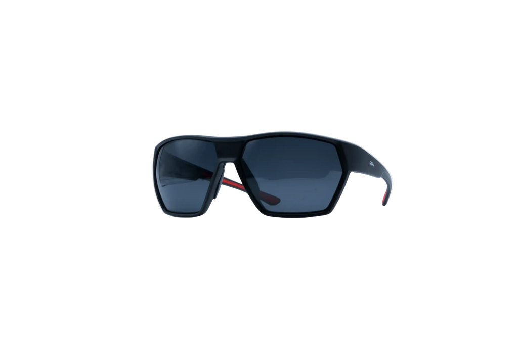 A pair of sporty wrap-around sunglasses with a matte black frame and dark gray lenses, featuring a small red accent on the temple arm, shown against a plain white background.