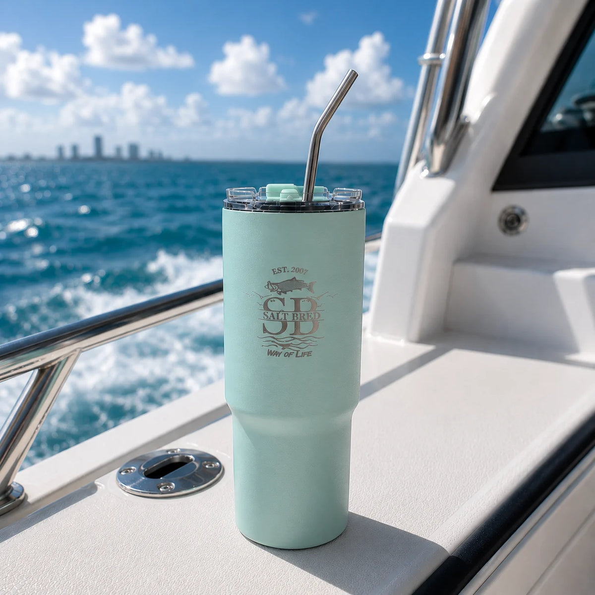 Mint green tumbler with straw on a boat with ocean view