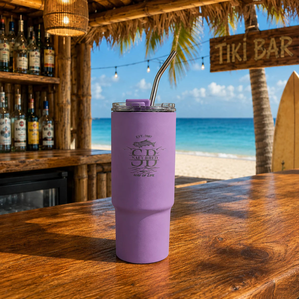 Purple tumbler with straw on a wooden table at a tiki bar with ocean view